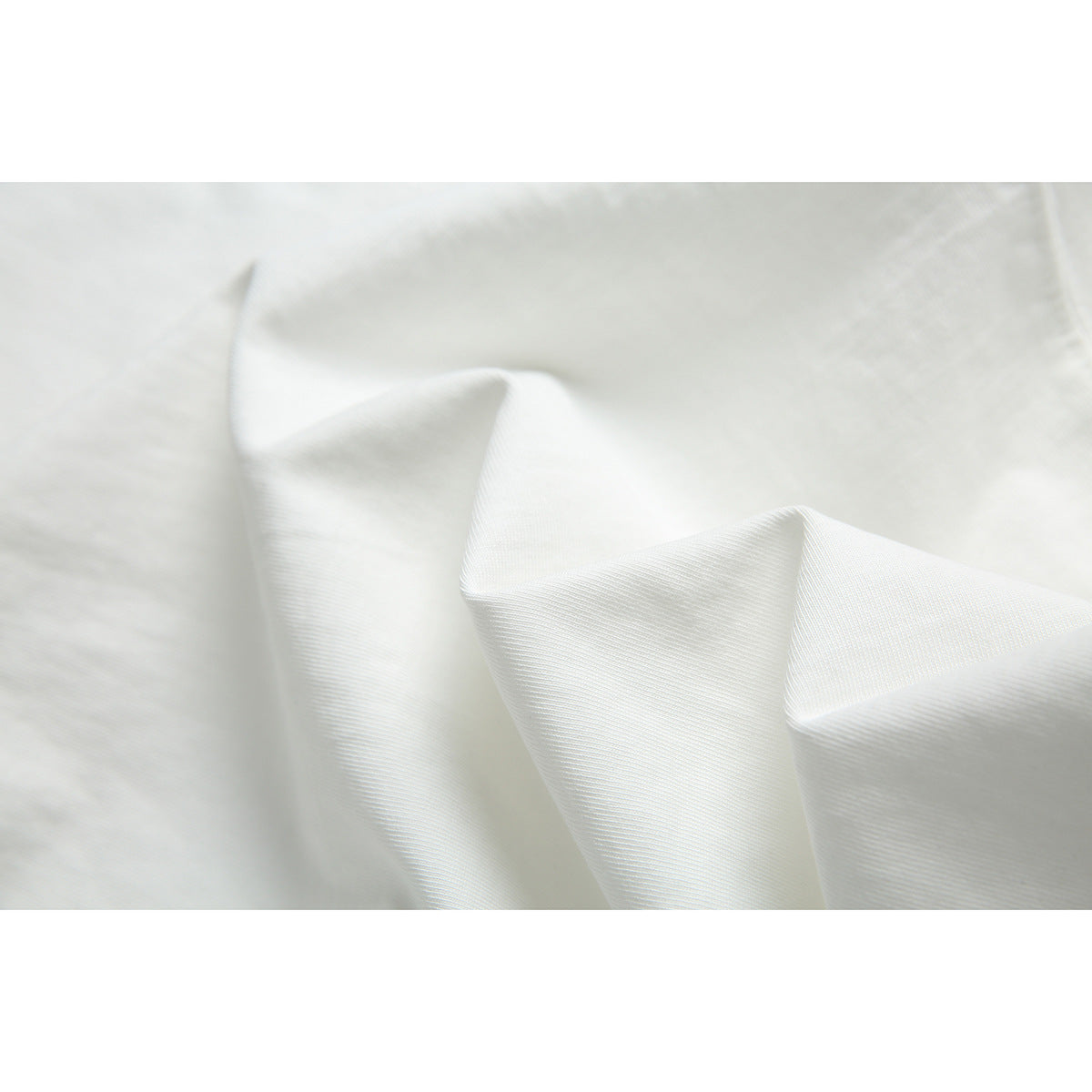 Close-up of white fabric arranged in soft folds, showing its surface texture.