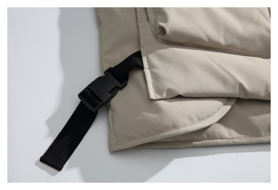 Close-up of a black adjustable buckle strap at the beige jacket's hem.
