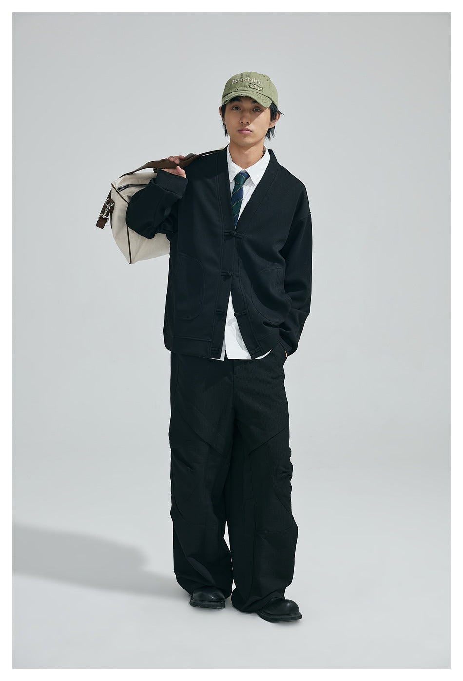 Model wearing a black loose-fit jacket with a stand collar, toggle closures and large front pockets; front view.