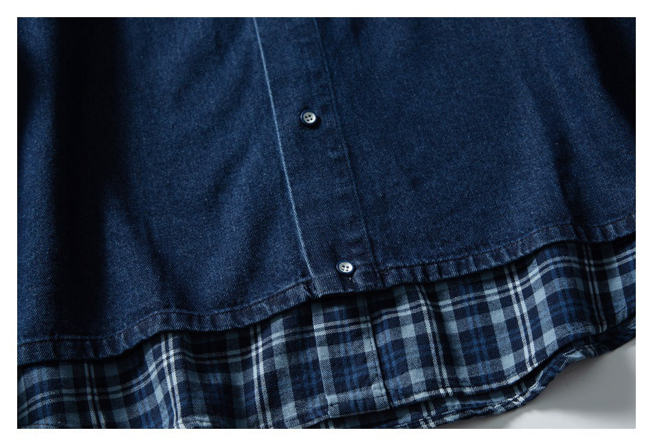 Close-up of the dark blue denim shirt hem, showing two buttons and a blue plaid underside.