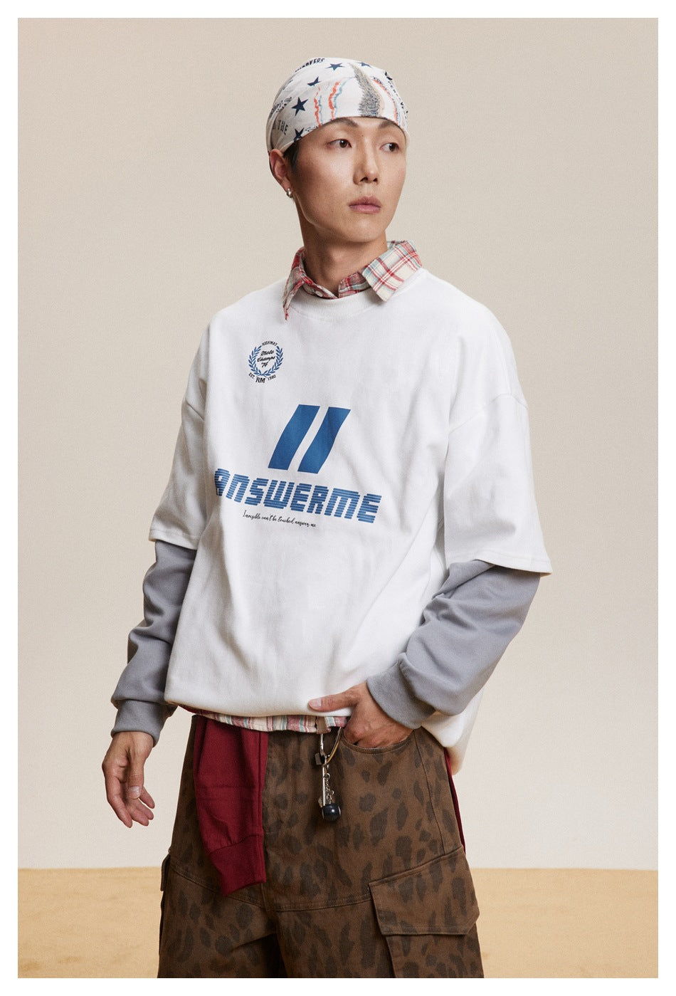 Front view of a model wearing a white sweatshirt with blue chest graphics over gray sleeves.