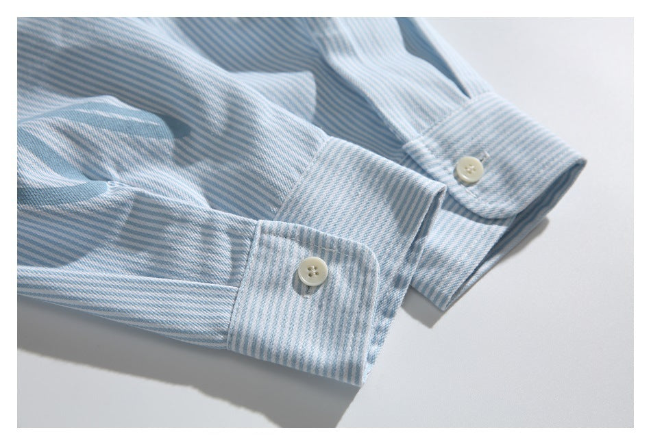 Close-up of two buttoned cuffs on a light blue and white striped shirt.