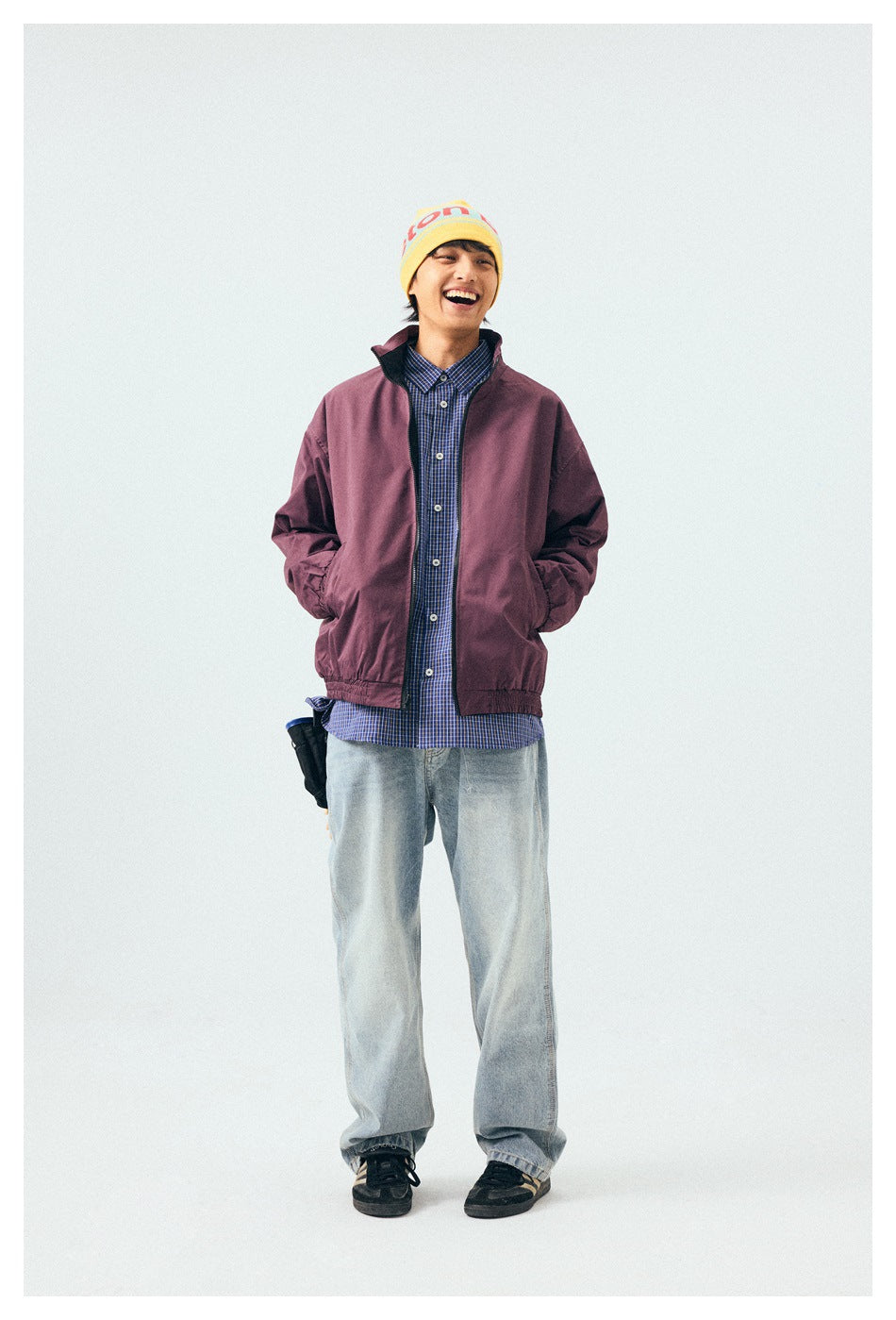 Full-length model wearing a plum zip-front jacket over a blue checked shirt with light-wash jeans.