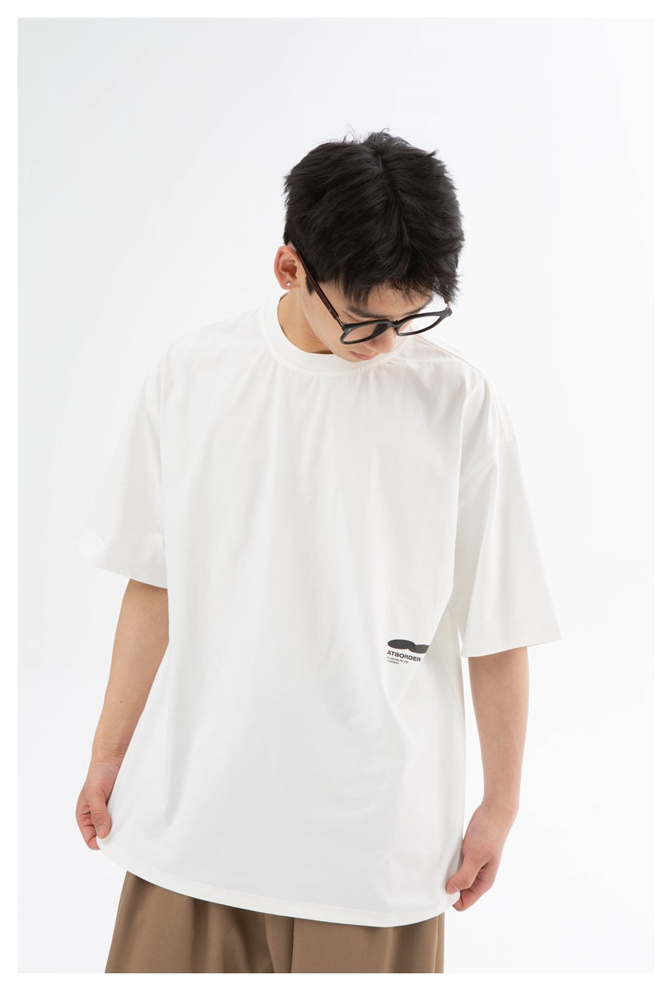 Model wearing an oversized white T-shirt, front view, with a small black logo near the lower side.