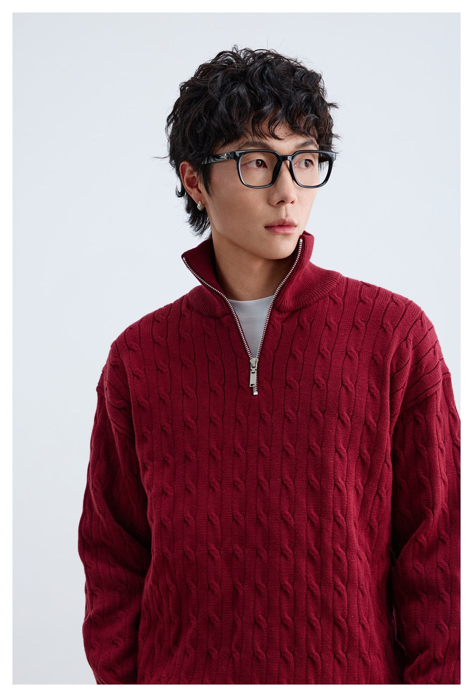 Close-up of a model wearing a burgundy cable-knit quarter-zip sweater with the collar open.