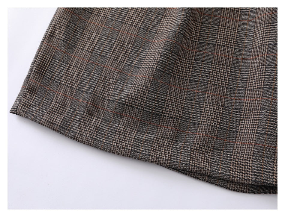 Close-up of the curved hem on brown-gray plaid trousers.