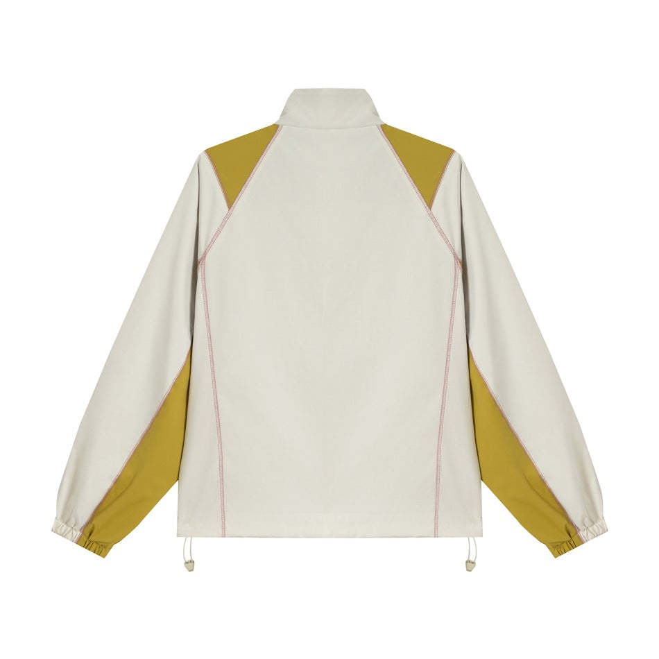 Back view of a cream jacket with mustard shoulder and sleeve panels, pink contrast stitching and an adjustable hem.