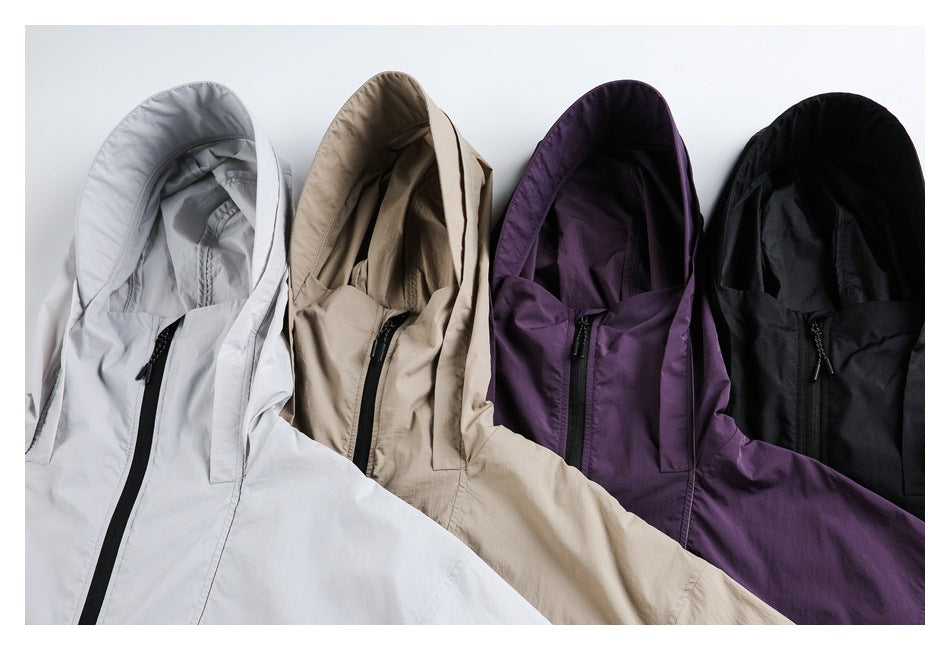 Four hooded jackets arranged together in light gray, beige, purple, and black, showing their front zippers and hoods.
