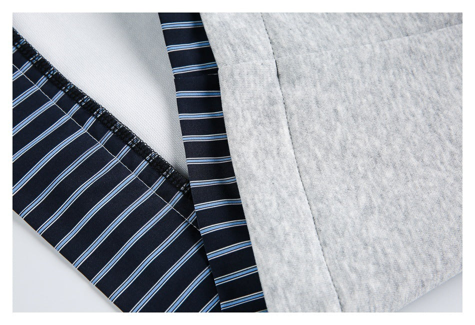 Close-up of the garment's light gray fabric and seam beside a navy striped inner panel and overlocked edge.