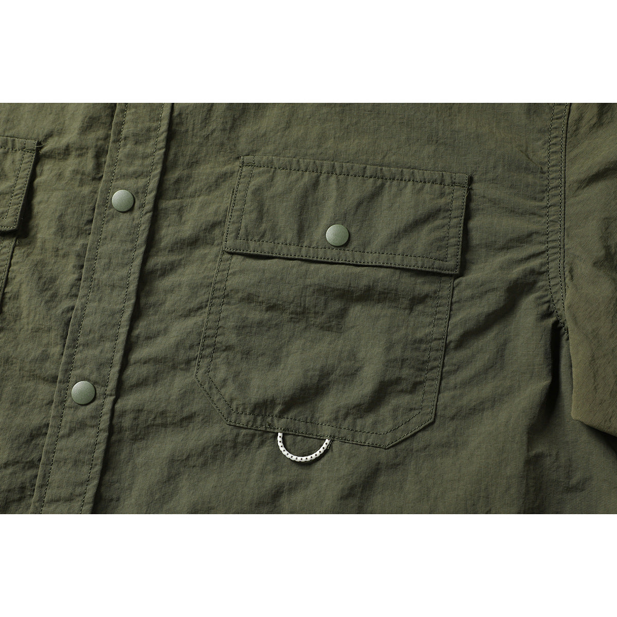 Close-up of an olive-green shirt's snap-button chest pocket and front placket.