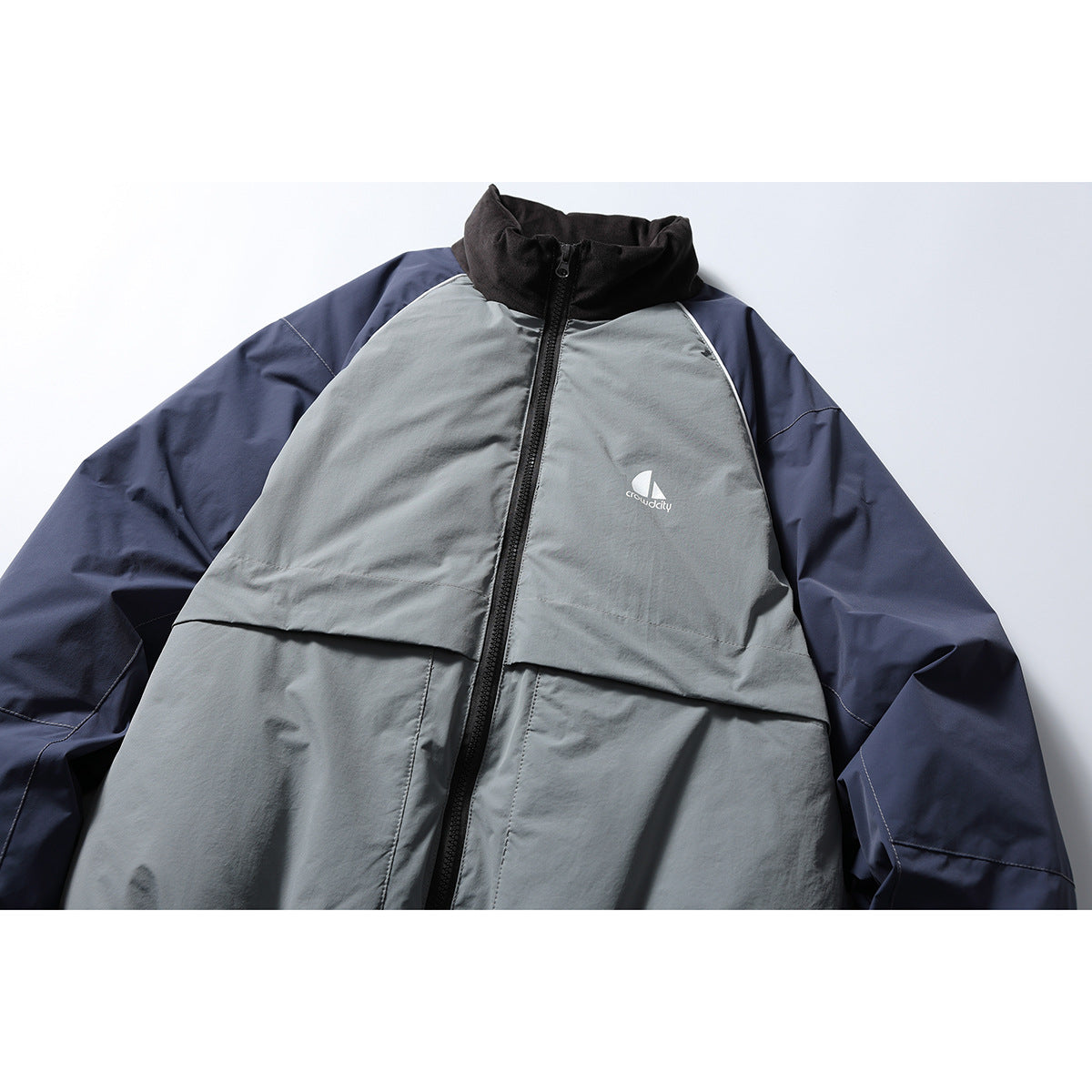 Front of a gray and navy color-block jacket with a black stand collar, full zipper, and white chest logo.