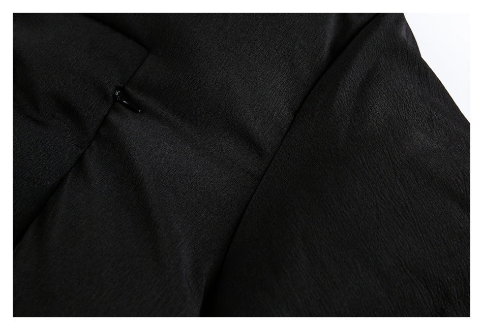 Close-up of black garment fabric with a stitched seam and small glossy black fastener.