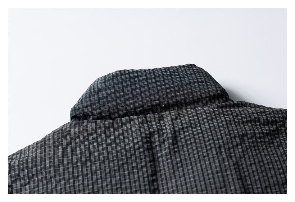 Close-up of overlapping panels and a seam on a dark gray plaid garment.