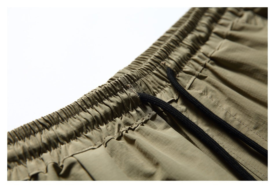 Close-up of olive-khaki shorts with an elastic waistband and black drawstrings.