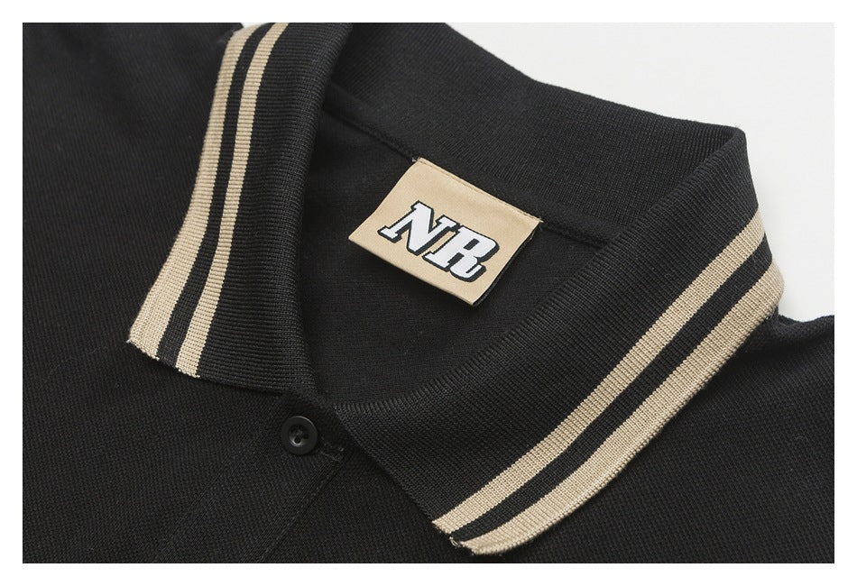 Close-up of a black polo collar with two beige stripes, a black button, and a beige NR neck label.