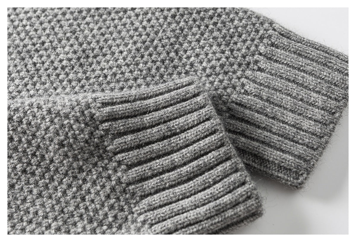 Close-up of gray textured knit sweater sleeves with ribbed cuffs.
