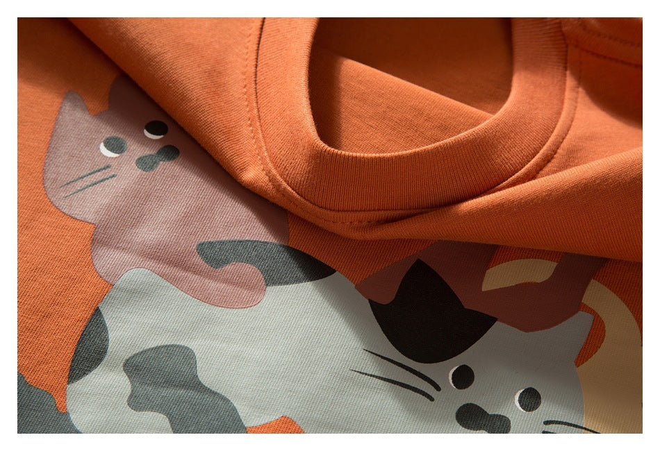 Close-up of an orange crew neckline above a multicolor cartoon cat print.