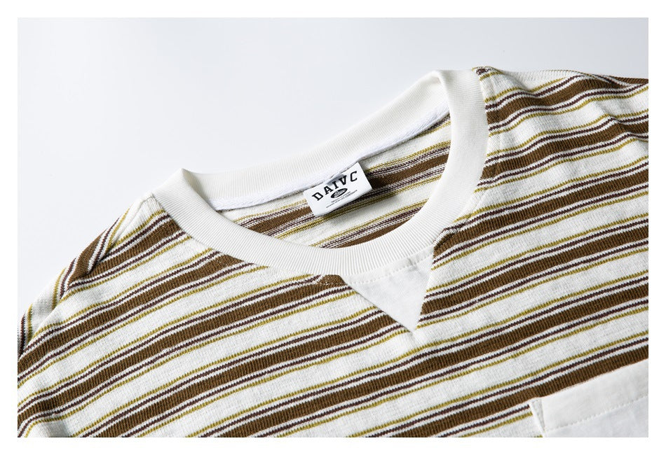 Close-up of a cream T-shirt with brown and olive stripes, showing the ribbed neckline, V insert, and chest pocket edge.