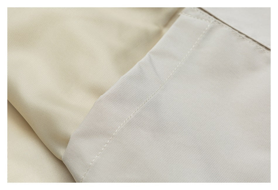 Close-up of a folded, stitched edge on a light beige garment.