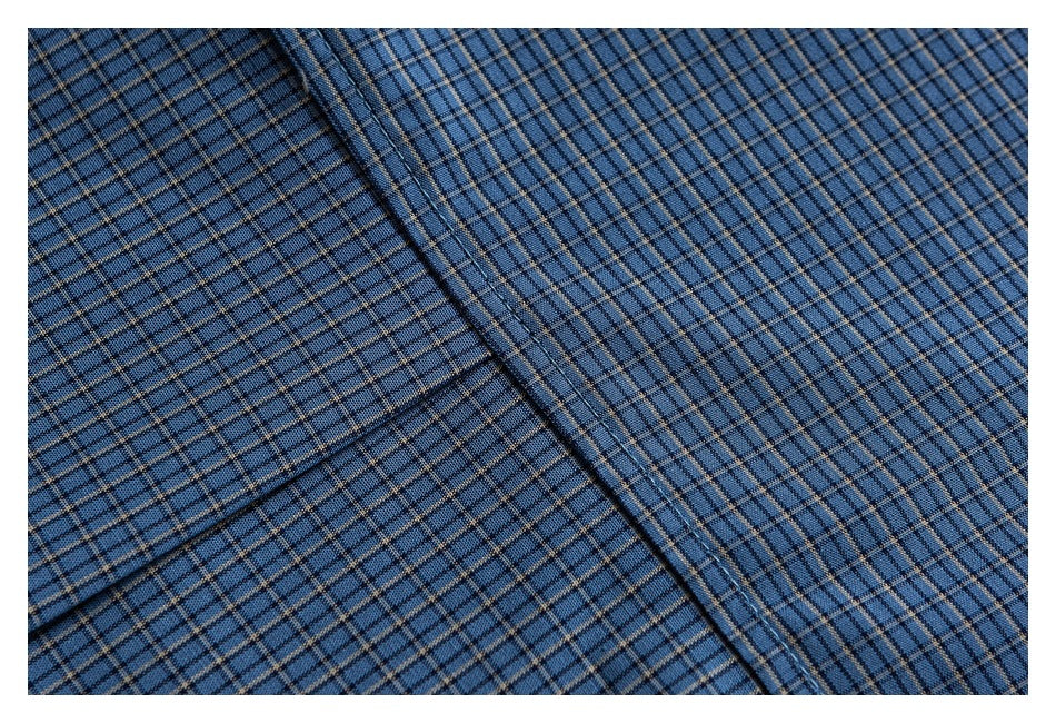 Close-up of intersecting seams on blue plaid shirt fabric.