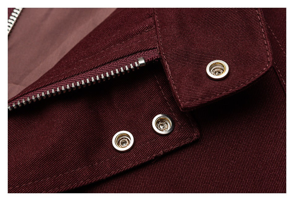 Close-up of a deep burgundy jacket zipper and metal snap fasteners beneath a flap.