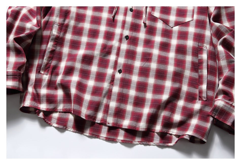 Close-up of the red plaid shirt's lower front, curved hem, and vertical side pockets.