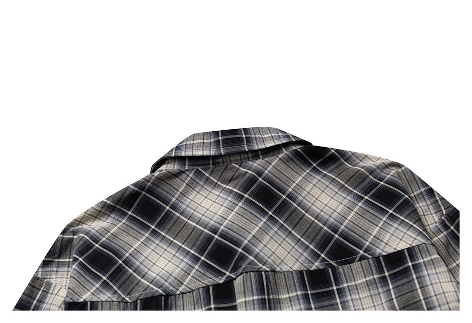 Partial back view of a black, gray, and cream plaid shirt, showing its collar and back yoke.