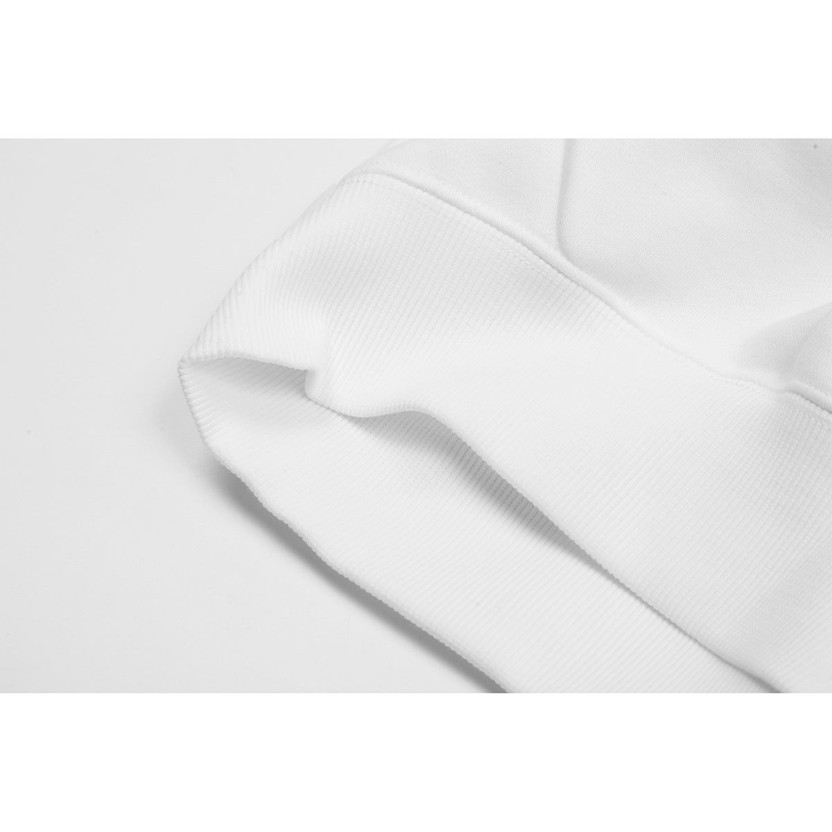 Close-up of a white sweatshirt's ribbed cuff and stitched seam.