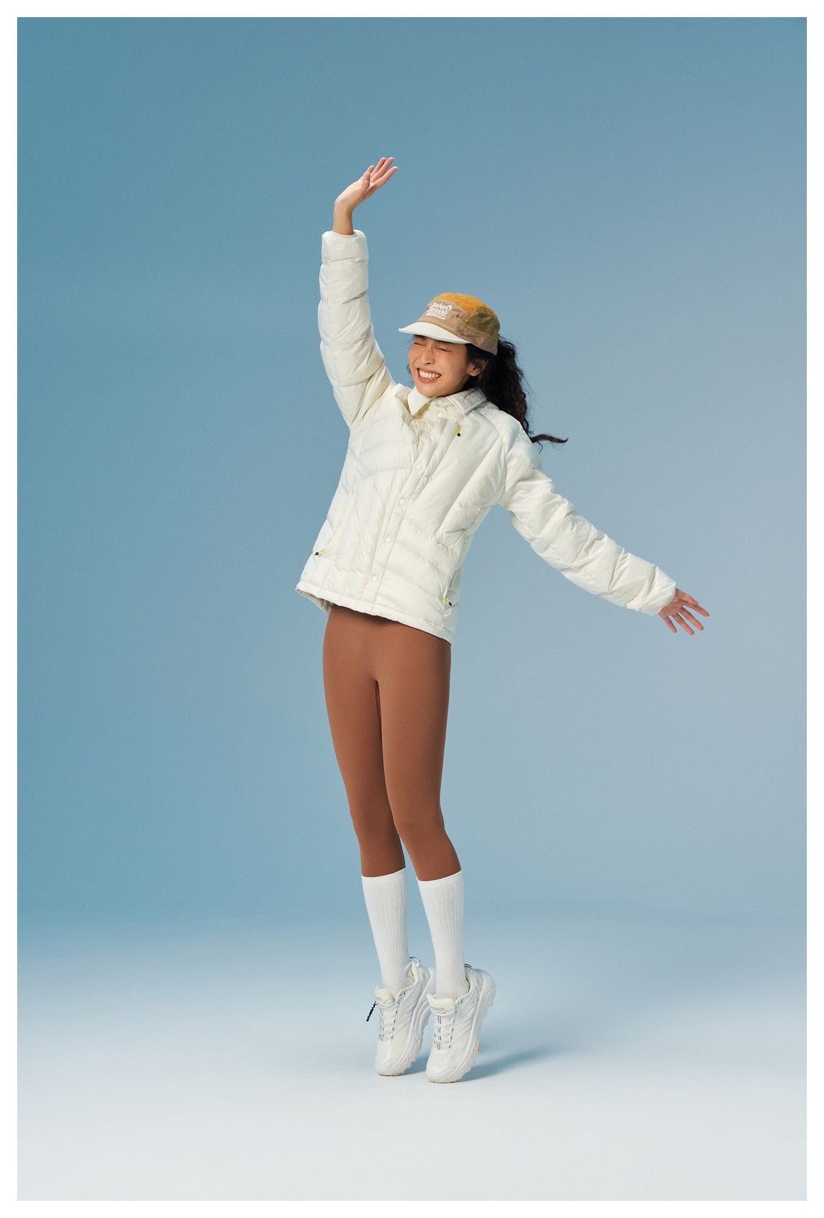 Model wears an ivory quilted jacket with arms raised, showing its front and relaxed fit.