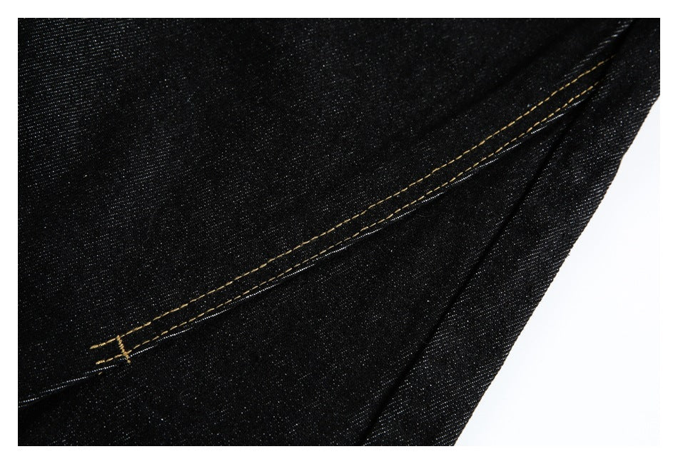 Close-up of black denim with diagonal golden contrast stitching.