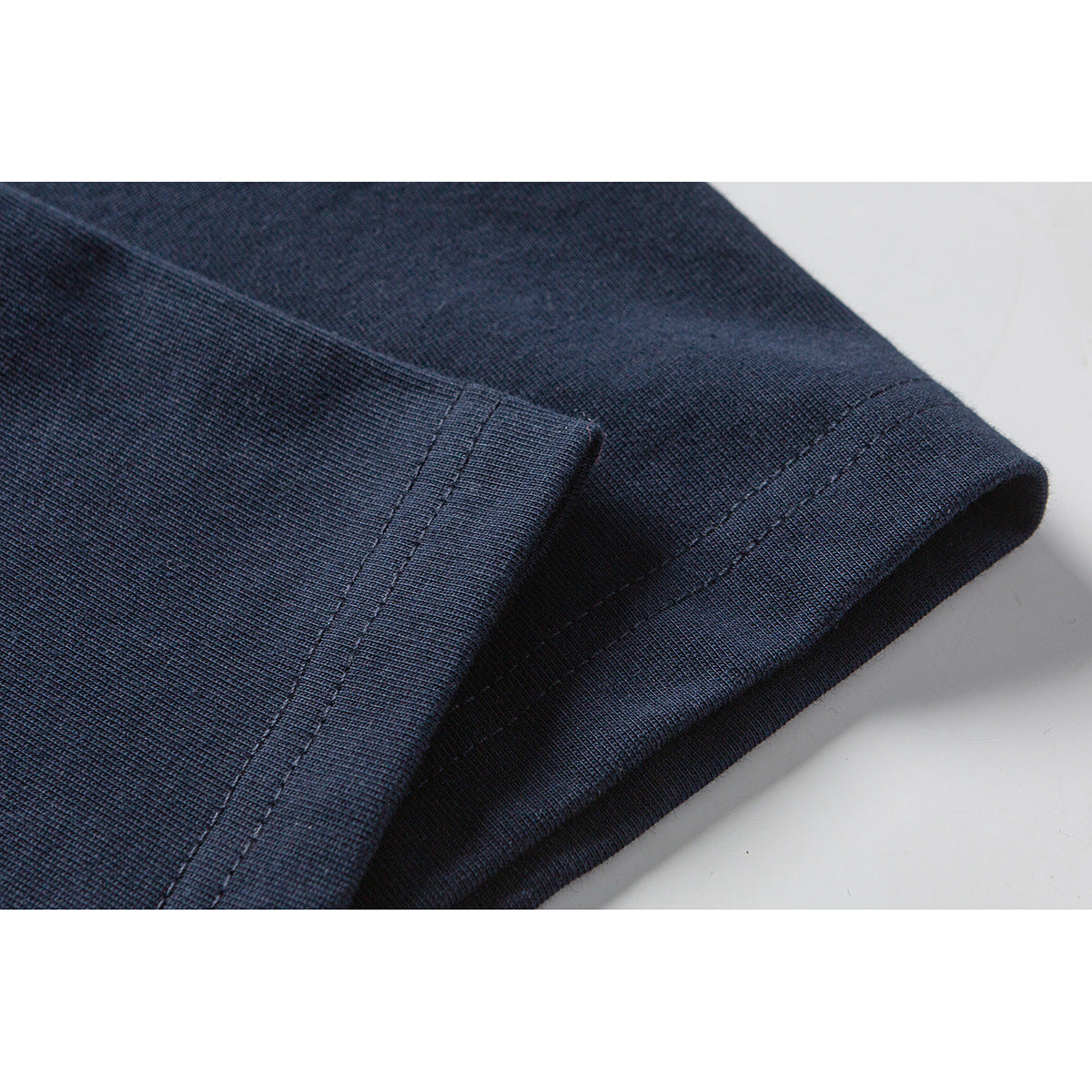 Close-up of the dark navy T-shirt’s short-sleeve hem and double-stitched edge.