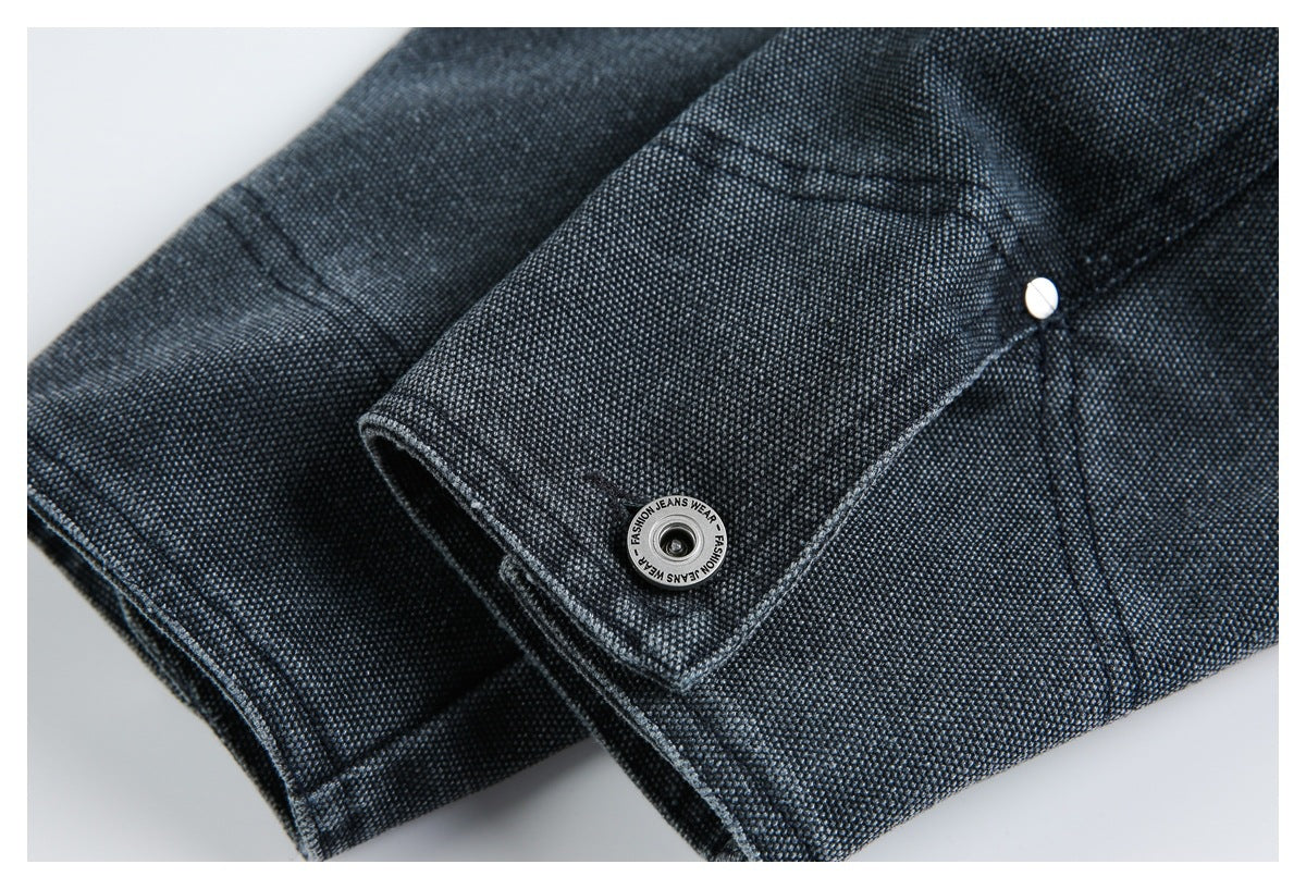 Close-up of dark charcoal-blue garment fabric with a textured weave, stitched seams, and a metal snap button.