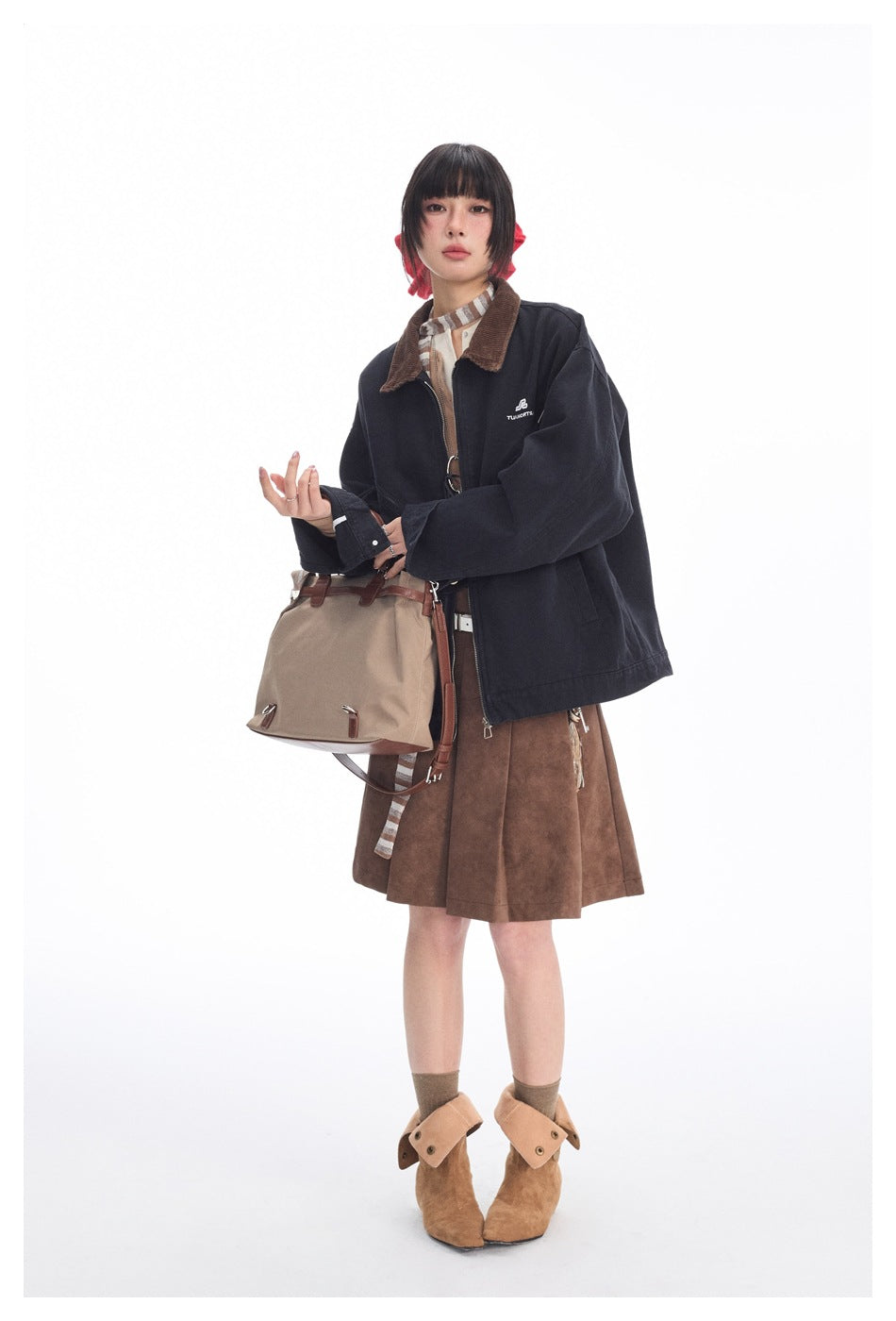 Model wearing a dark navy jacket with a brown collar, paired with a brown skirt and tan boots, shown from the front.
