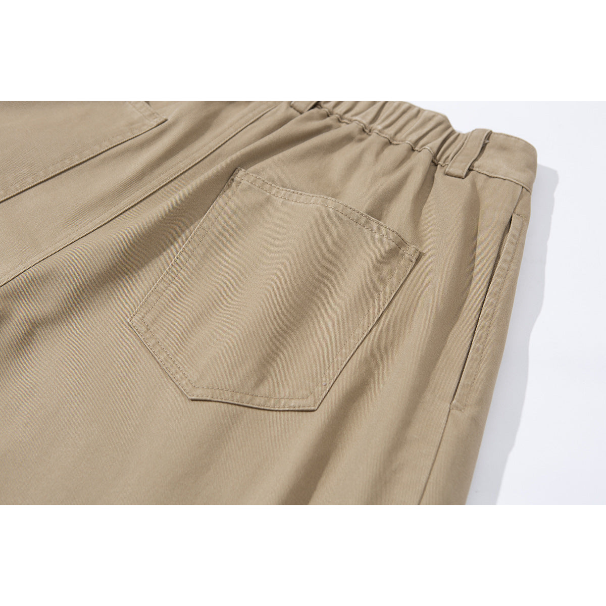 Close-up of tan shorts showing a stitched rear pocket and gathered waistband.