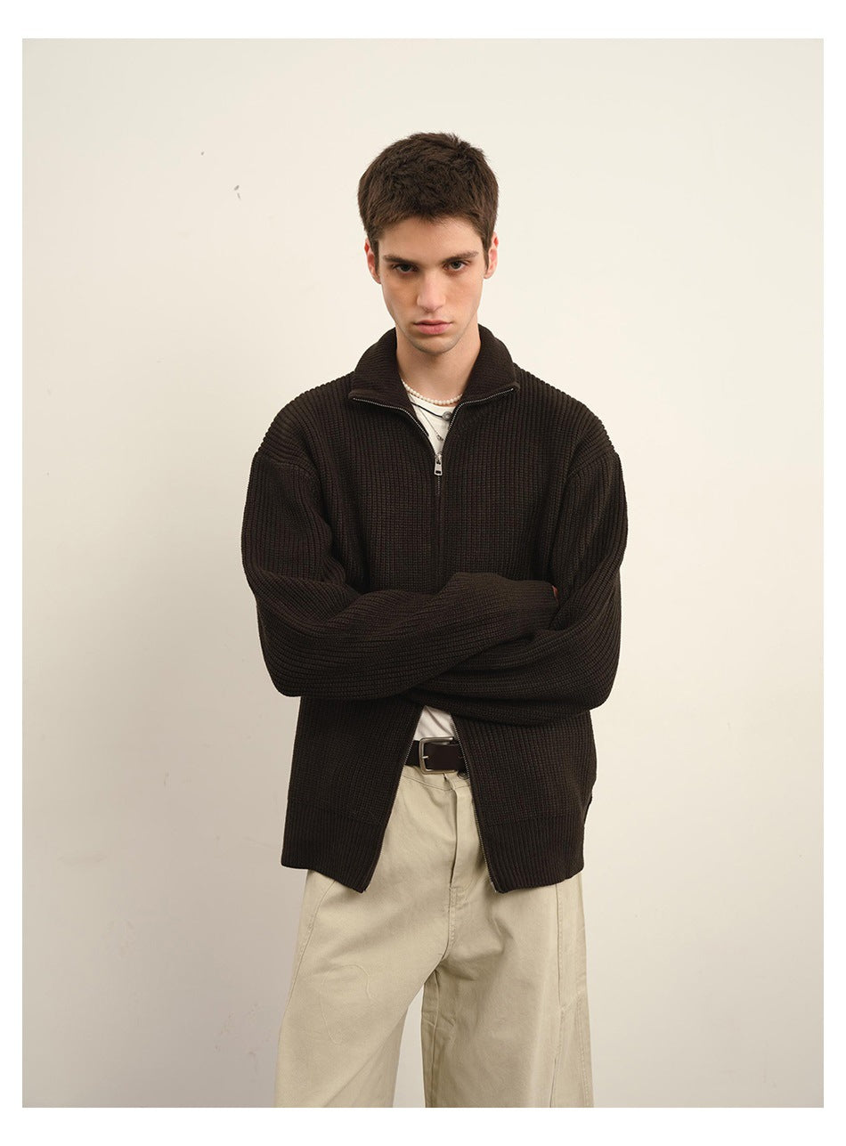 Closer front view of a model wearing a dark brown ribbed zip-front sweater with a high collar.