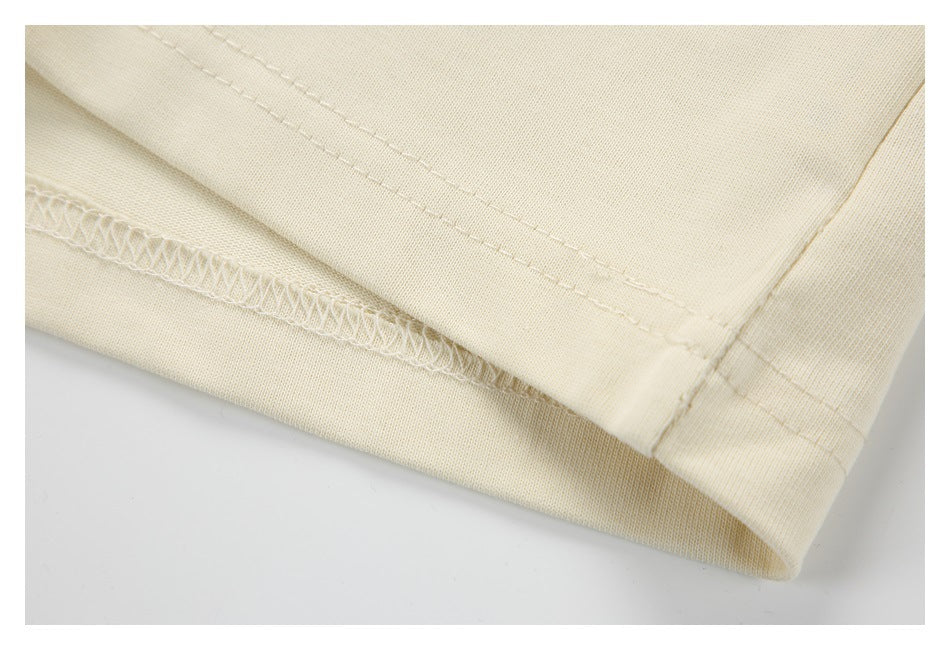 Close-up of an ivory garment hem showing double stitching and an overlocked seam.
