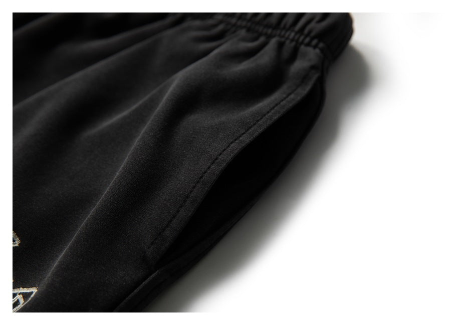 Close-up of the side seam and pocket opening on black jogger pants.