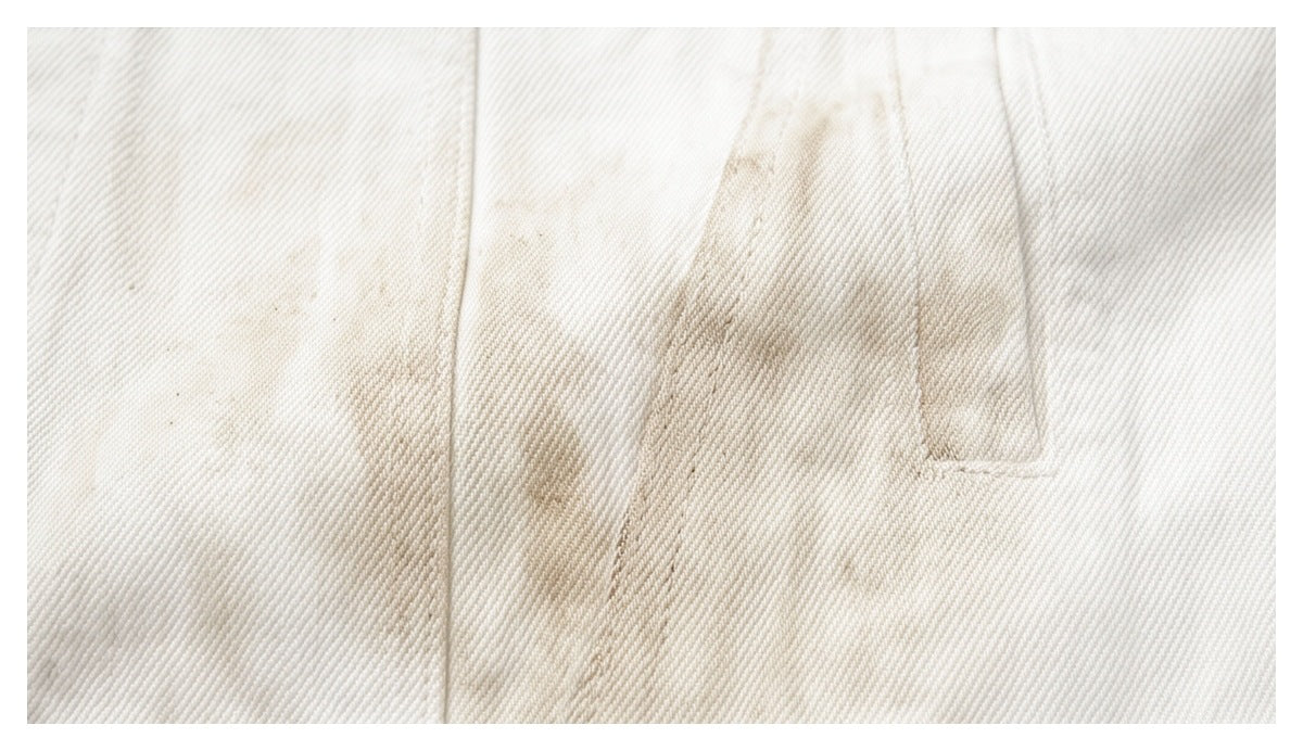 Close-up of ivory jacket fabric showing a stitched seam and narrow welt pocket opening.