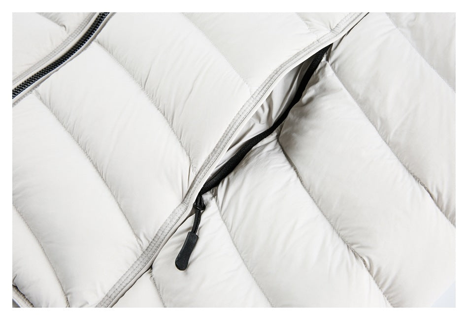 Close-up of a white padded jacket showing a partially open pocket zipper and quilted panels.