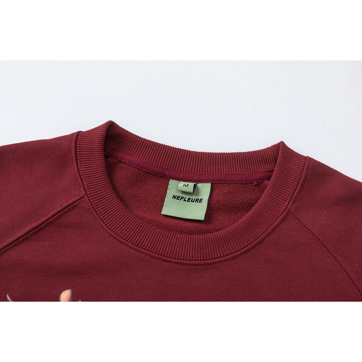 Close-up of a burgundy sweatshirt neckline with ribbed collar and a sewn NEPLEURE size M label.