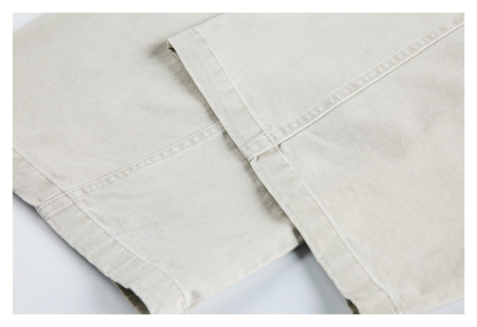 Close-up of the stitched hem and seams on light beige trousers.