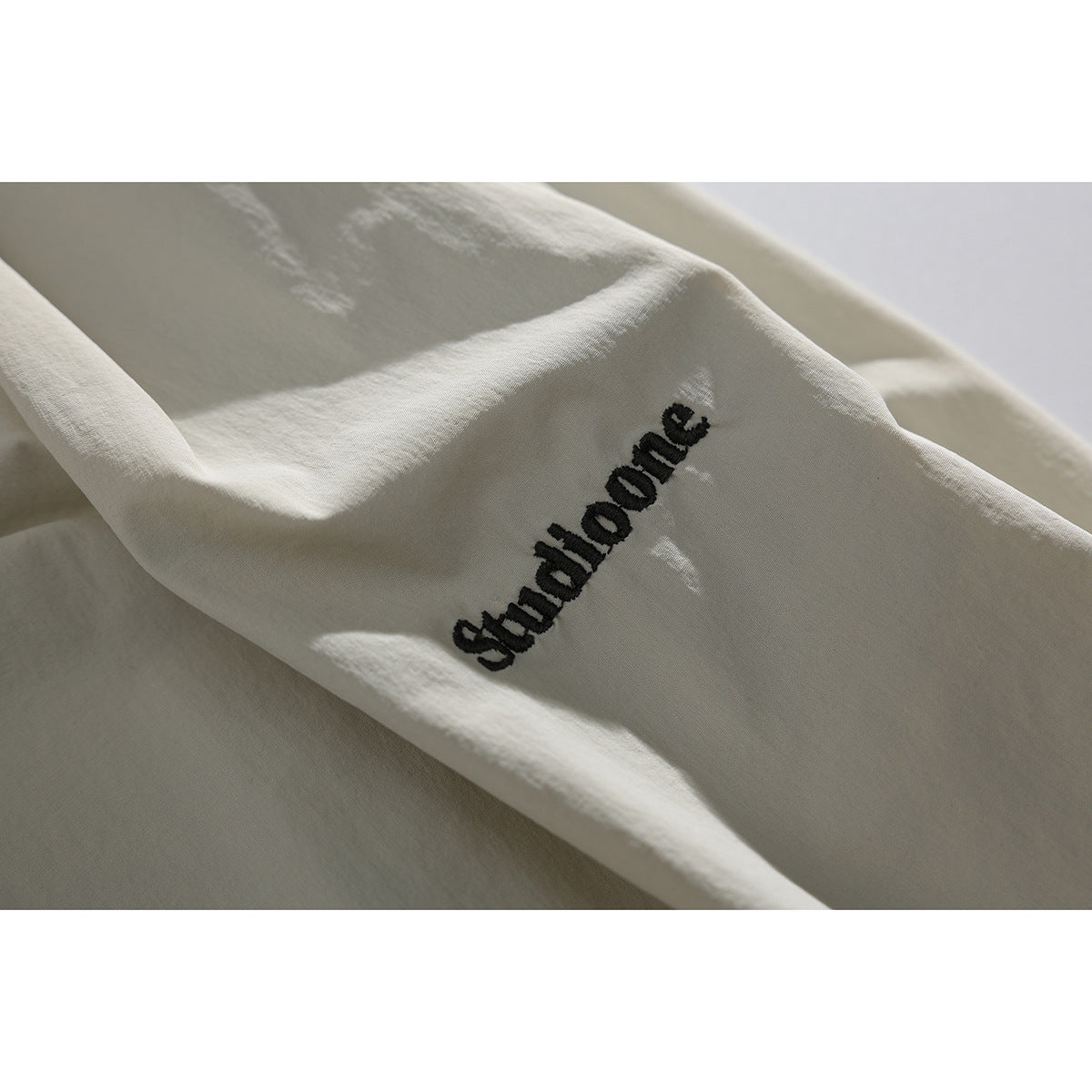 Close-up of light beige shorts with black embroidered lettering on the fabric.