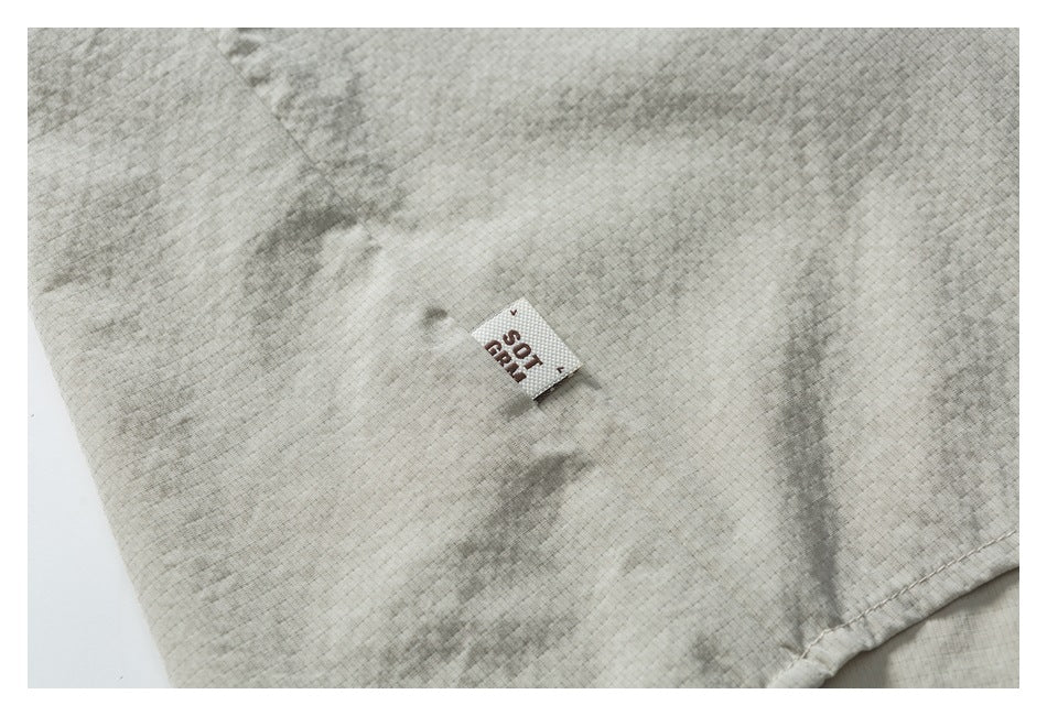 Small woven label on light beige textured garment fabric, shown in close-up.