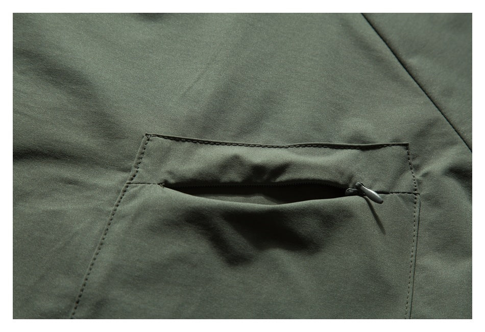 Close-up of a rectangular zip pocket with a dark pull on dark olive-green fabric.
