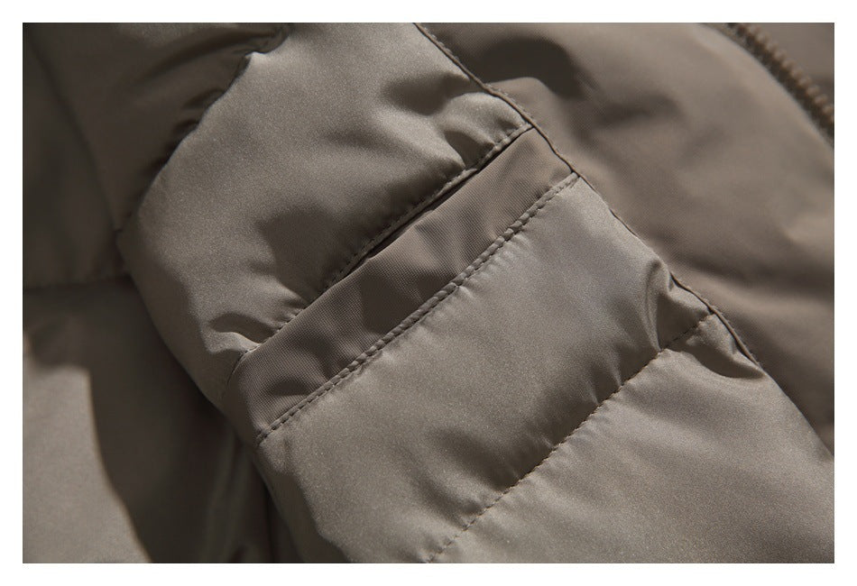 Close-up of taupe padded jacket fabric showing diagonal stitched seams and quilting.