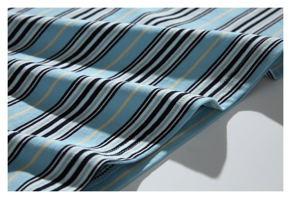 Close-up of light blue striped knit fabric draped in folds, with black, white, and thin tan stripes and a finished edge.