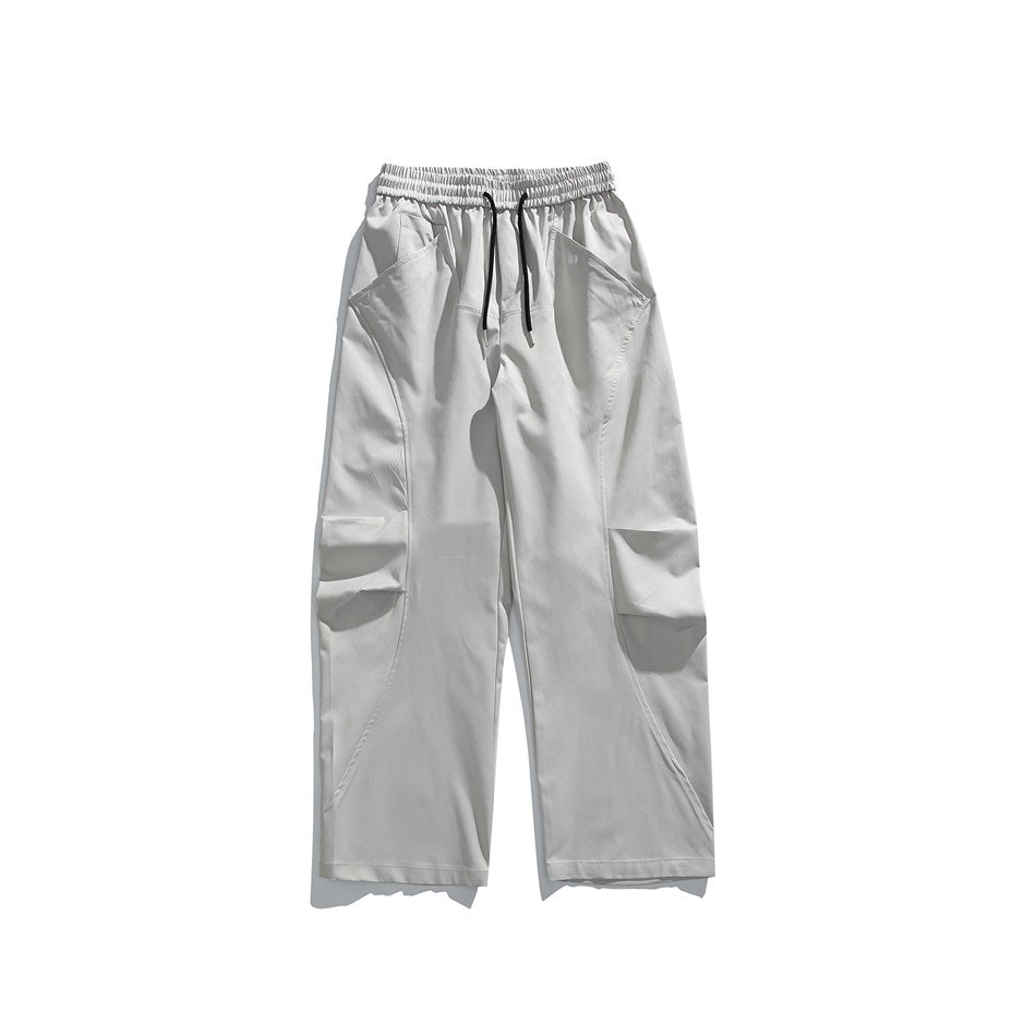 Light gray wide-leg pants flat lay with drawstring elastic waist, curved leg seams and large pleated thigh pockets