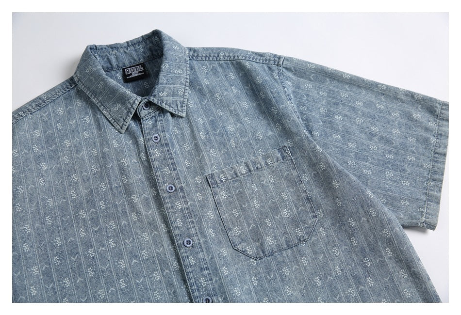 Angled flat-lay view of a blue-gray patterned short-sleeve button-up shirt with a chest pocket.
