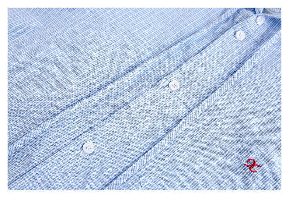 Close-up of a blue-and-white check shirt front with white buttons and a red embroidered symbol.