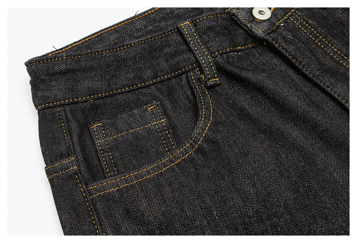 Close-up of dark indigo jeans showing the front pocket, small coin pocket, waistband and golden stitching.